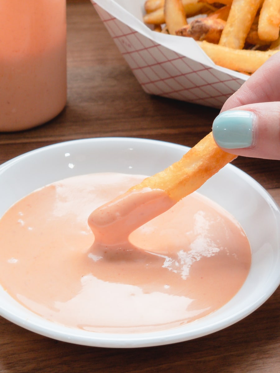 dipping a fry in spicy sriracha mayo