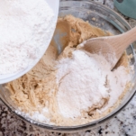 adding dry cookie dough mixture to wet cookie dough mixture in a bowl