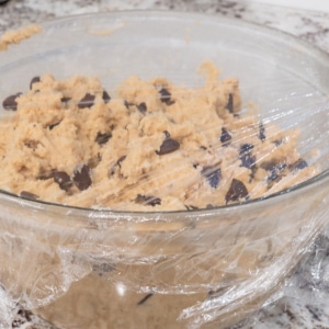 bowl of chocolate chip cookie dough covered with plastic wrap