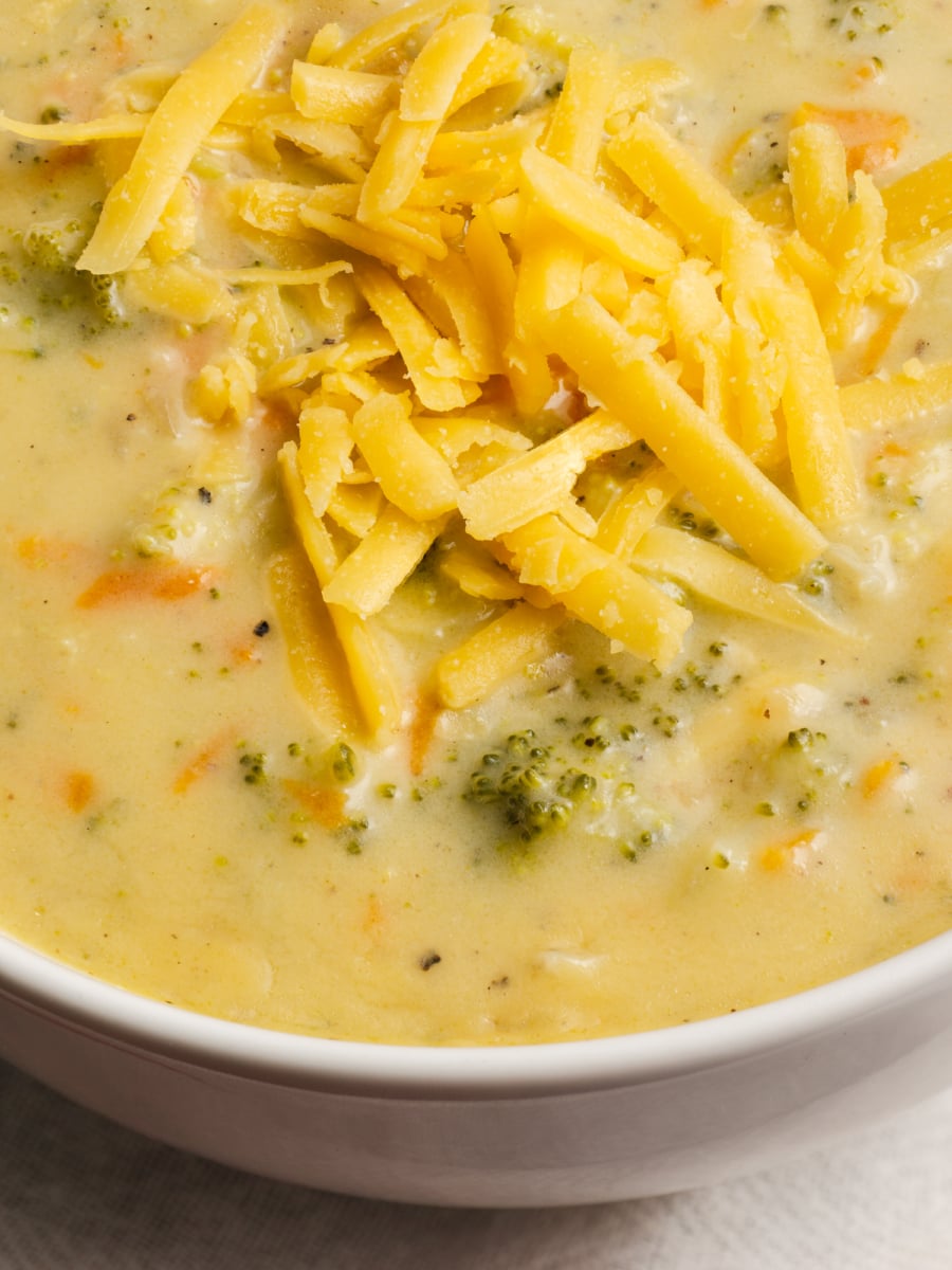 close up of cheddar cheese on broccoli and cheese soup