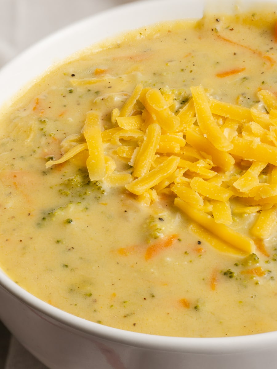 a bowl of broccoli cheese soup topped with shredded cheddar