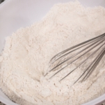 mixture of flour, cornstarch, baking powder, baking soda, and salt in a bowl with a whisk