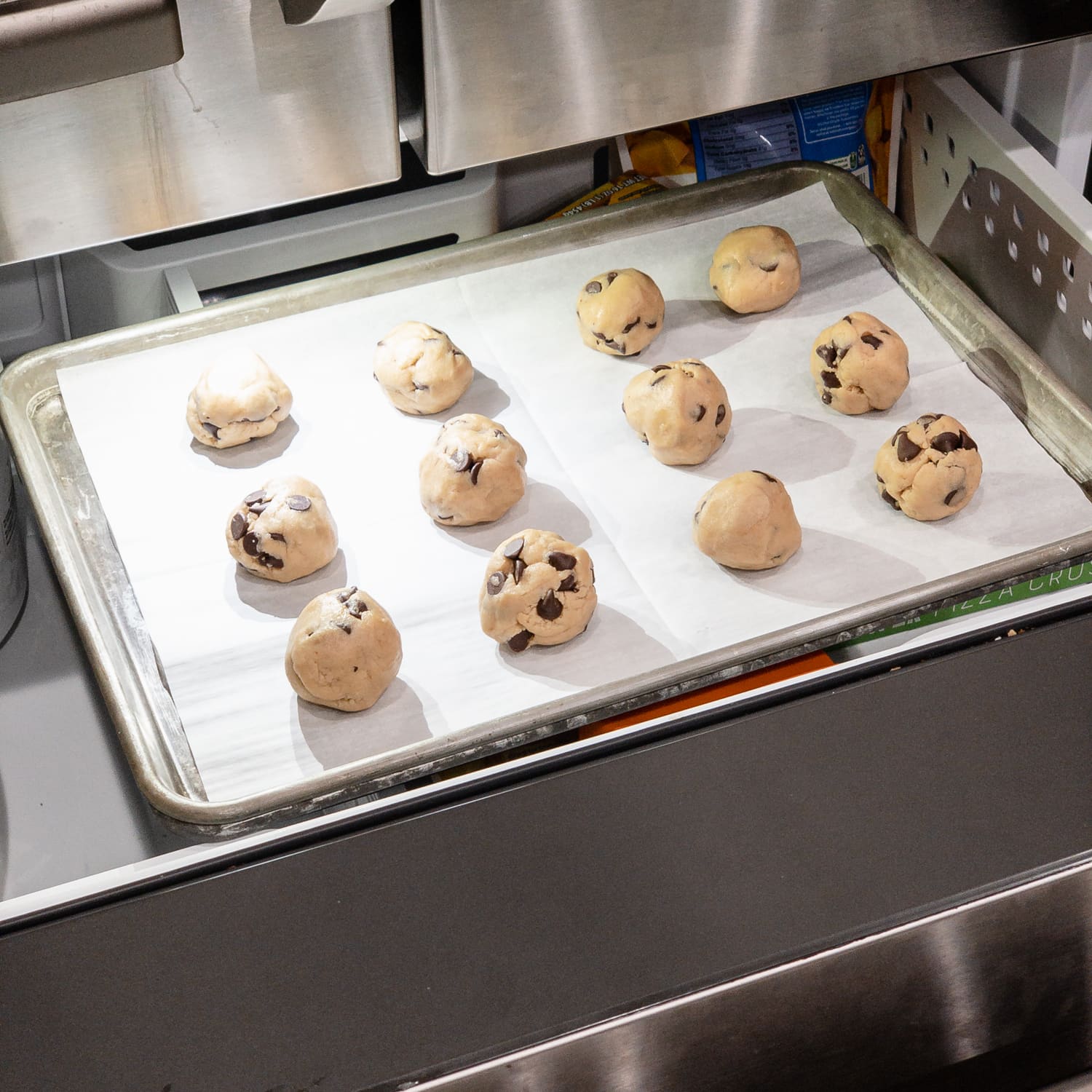 placing chocolate chip cookie dough balls on baking sheet into a freezer