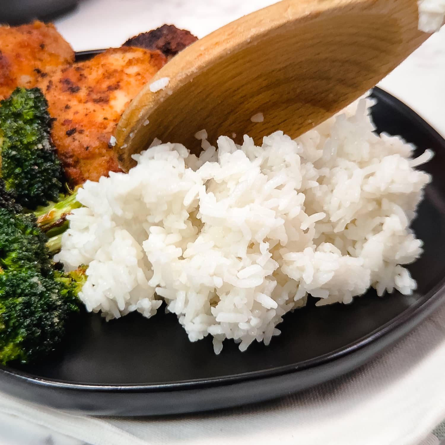 serving instant pot jasmine rice on a plate with chicken thighs and roasted broccoli