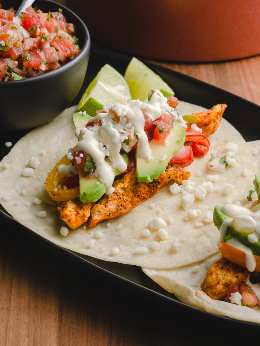 chicken fajitas topped with avocado, pico de gallo, and sour cream