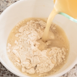 adding chicken stock to cornflour in a bowl