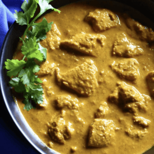 close up of a bowl of butter chicken garnished with parsley