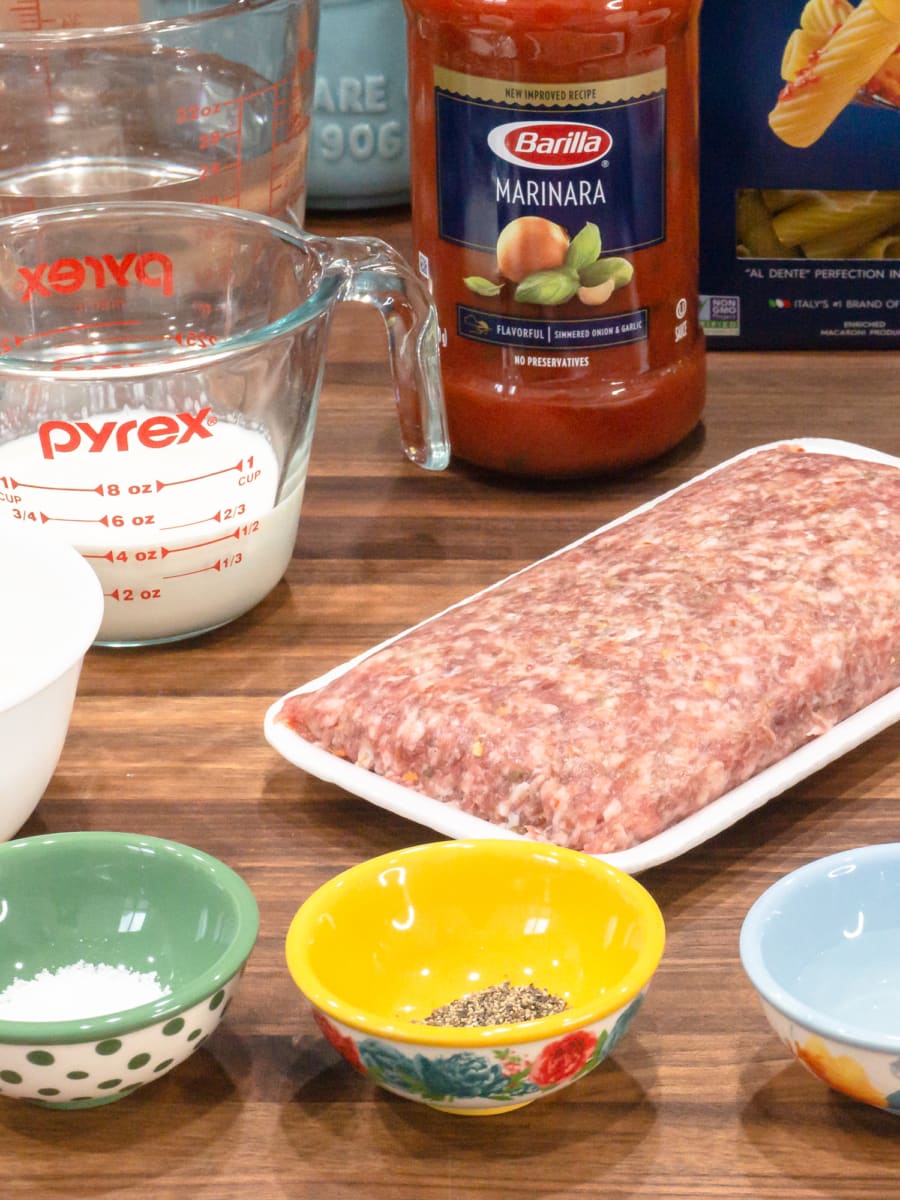 ingredients for instant pot creamy sausage rigatoni including pasta sauce, rigatoni pasta, ground sausage, cream, and spices