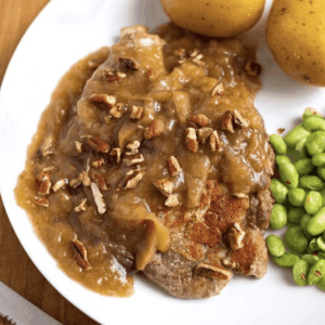 autumn apple pork chops topped with pecans on a dinner plate