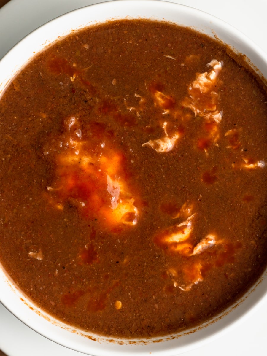 overhead shot of a bowl of bean soup with egg and tabasco sauce