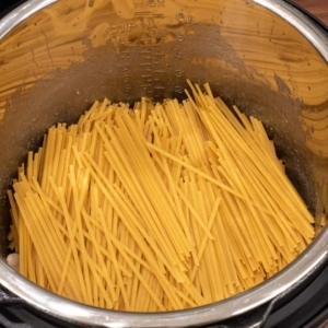 linguine layered on top of the cooked chicken in the pressure cooker liner