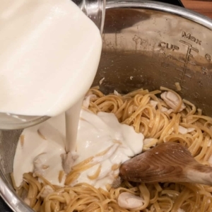 adding the alfredo sauce base to the linguine pasta and chicken