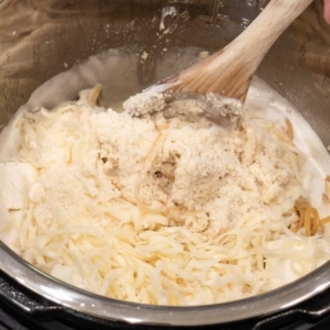 mixing the pasta with the alfredo sauce and cheeses