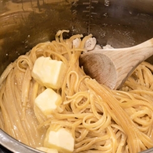 adding butter and mixing into pasta so that it will melt