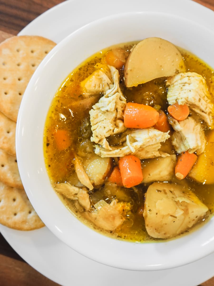 a bowl of chicken vegetable soup with a side of crackers