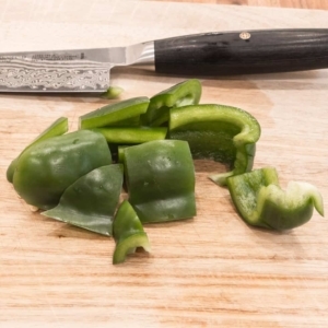 rough cut green bell pepper on a wooden board