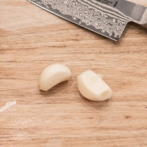 two cloves of garlic on a wooden board