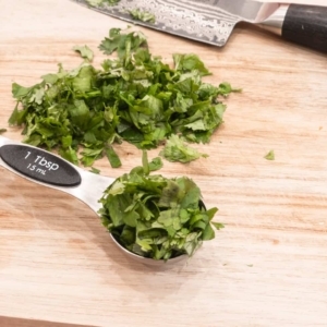 a tablespoon of chopped cilantro on a wooden board