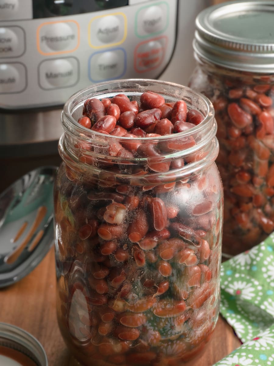 a glass mason jar filled with red beans cooked in the instant pot