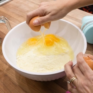 cracking an egg into a large mixing bowl with lemon cake mix