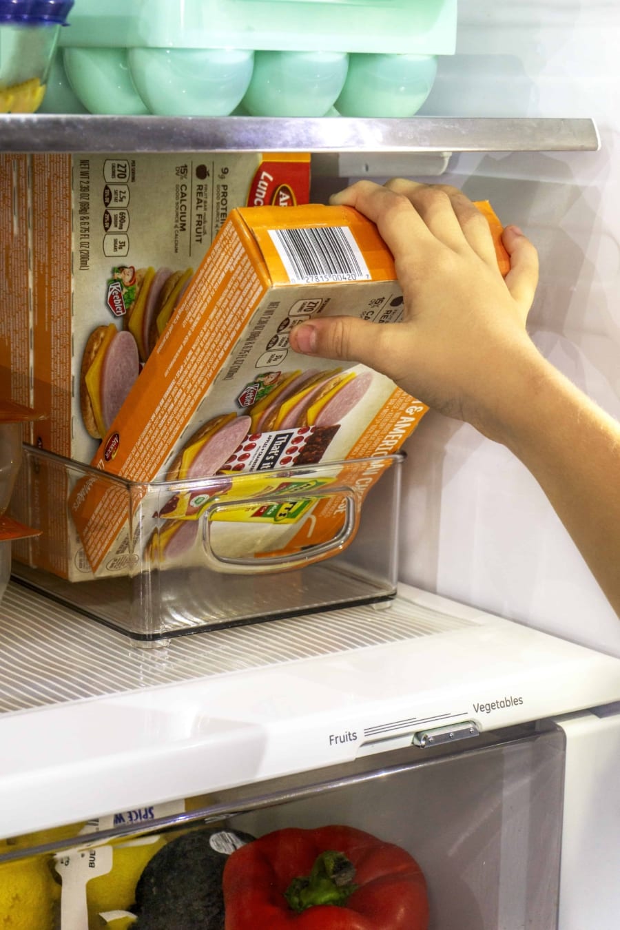 a child's hand pulling a box of armour lunchmakers plus drink from refrigerator