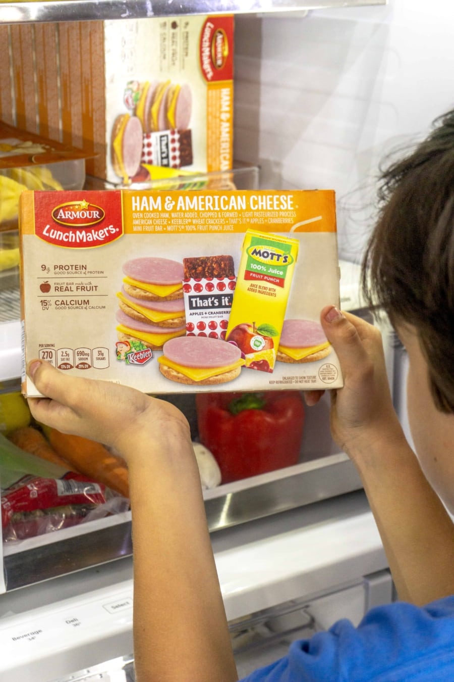 a boy taking out a box of armour lunchmakers from the refrigerator