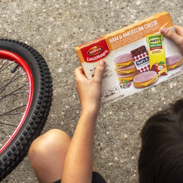 a view from above of a bike and a child holding a box of armour lunchmakers and drink ham and american cheese