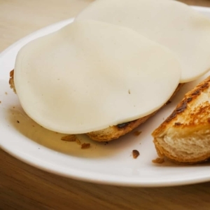 two slices of provolone cheese layered on top of a slice of toasted french bread