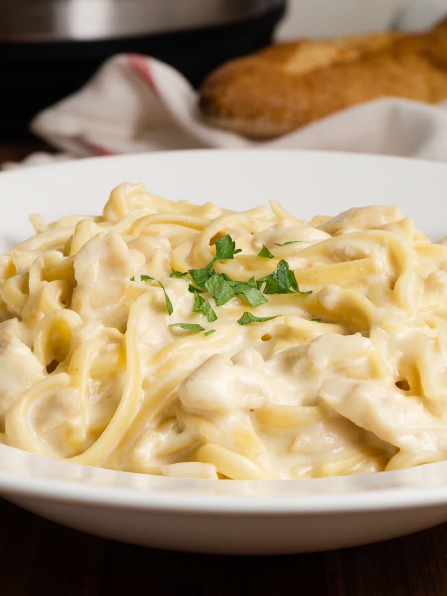 a white bowl of super creamy instant pot chicken fettuccine alfredo