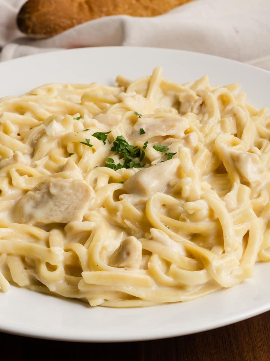 a delicious and creamy bowl of instant pot chicken fettuccine alfredo topped with a bit of parsley