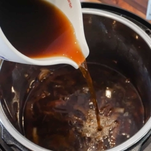 adding beef broth to the electric pressure cooker