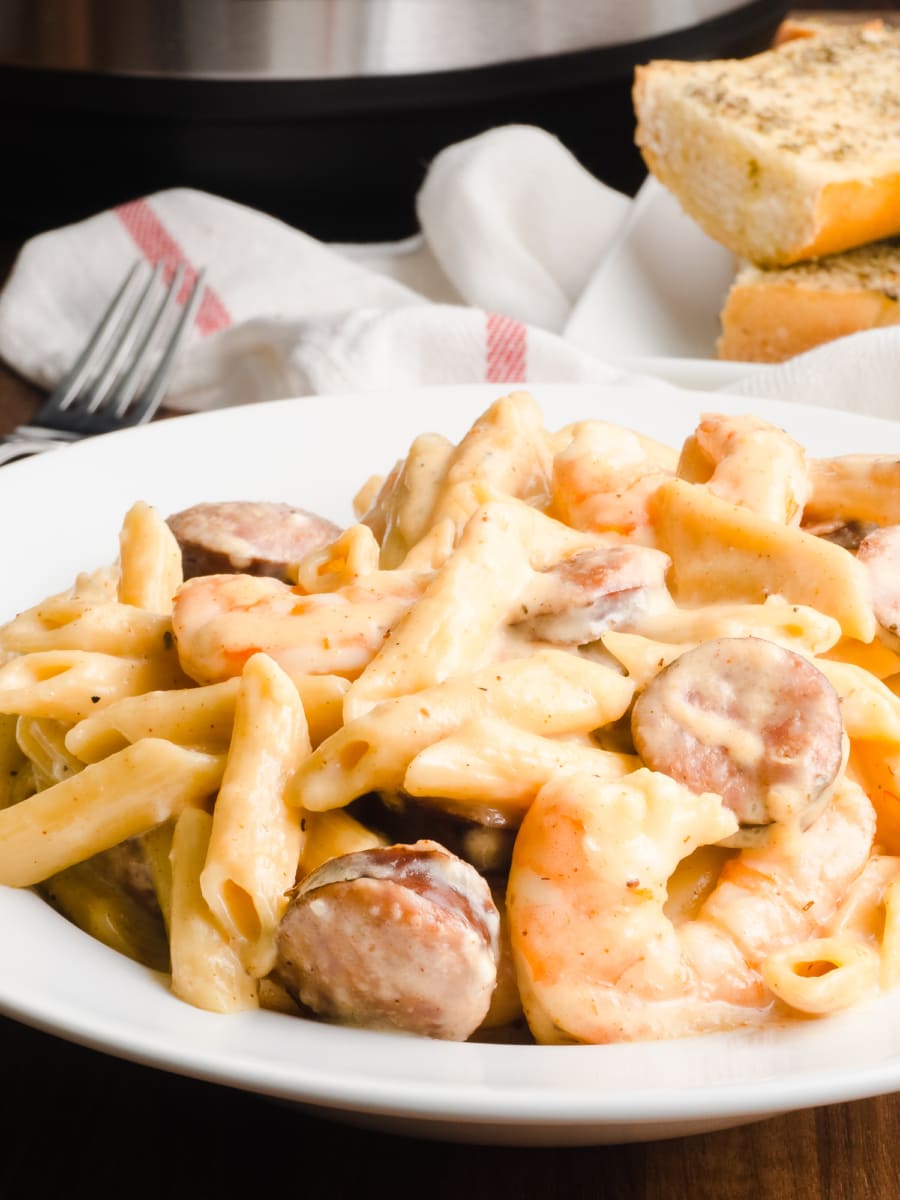 plate of instant pot cajun shrimp alfredo with garlic bread in background