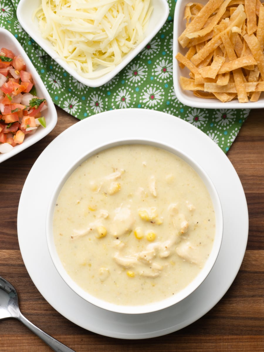 a view from above of a creamy bowl of instant pot enchilada soup, cheese, pico, and tortilla strips