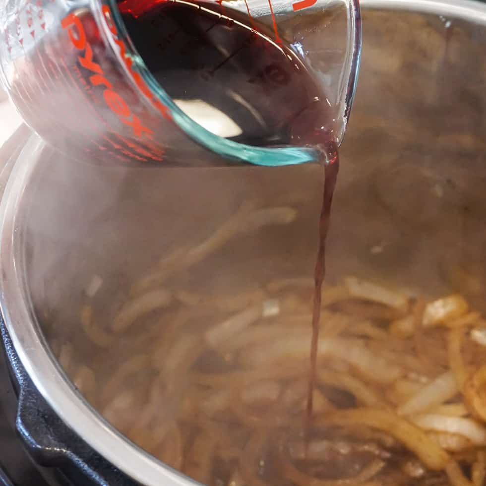 pouring red wine over sautéed onions in the instant pot