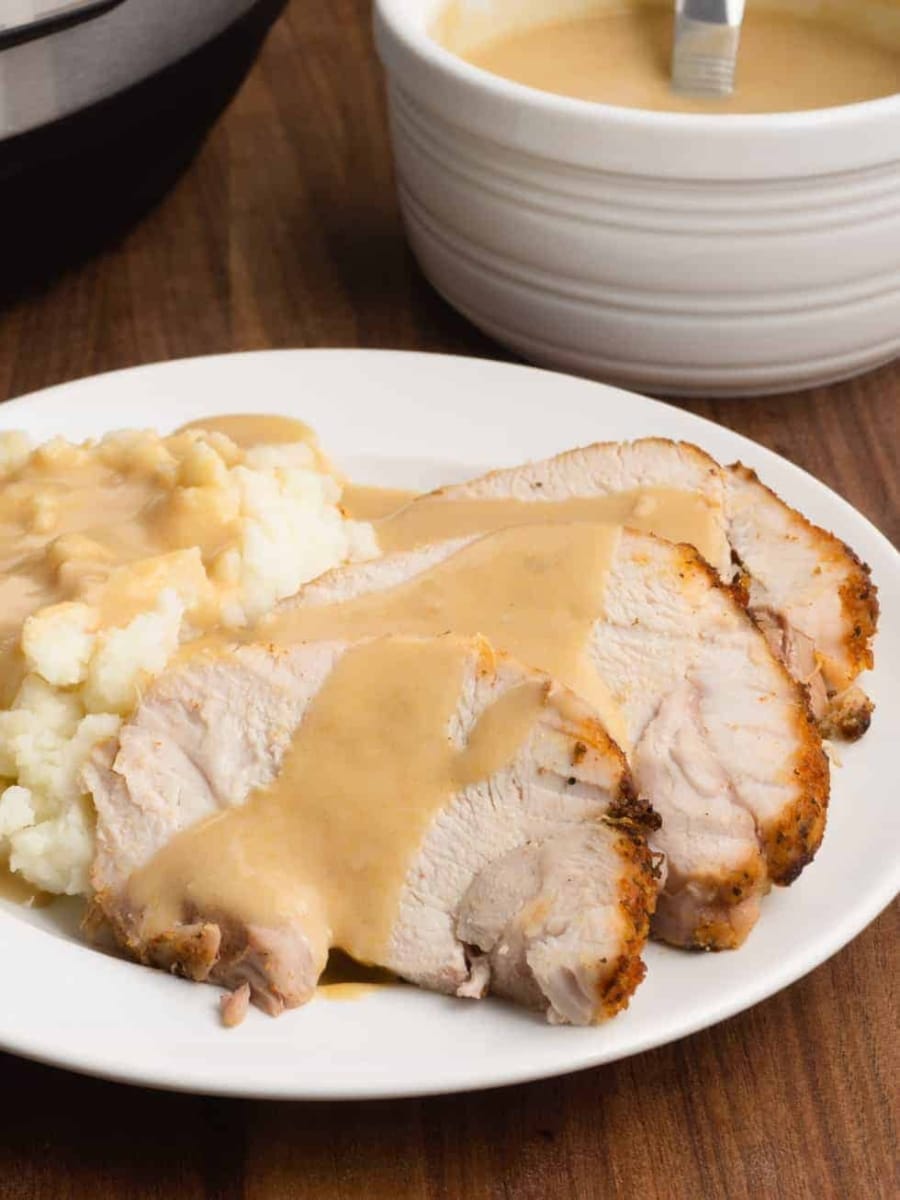 a plate of sliced turkey roast with mashed potatoes and gravy