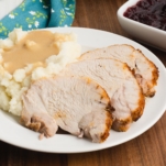 a close up of a plate with sliced instant pot turkey roast, mashed potatoes, and gravy