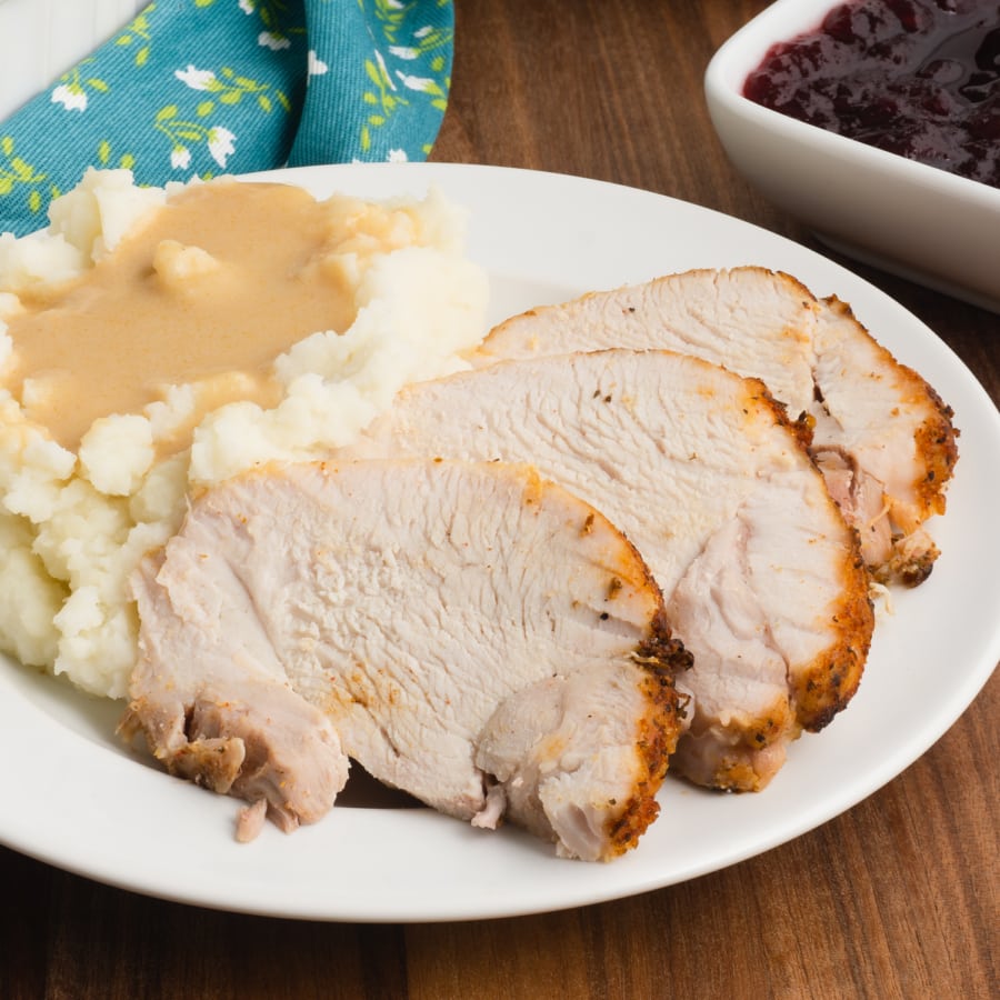 a close up of a plate with sliced instant pot turkey roast, mashed potatoes, and gravy