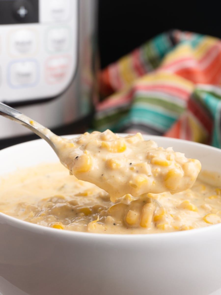 a spoonful of vanilla jalapeño corn chowder being scooped out of a bowl and an instant pot in the background