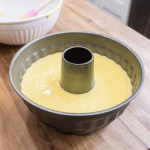 a large bundt cake pan with lemon cake batter filling it about halfway up