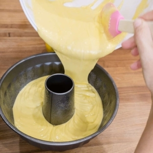 pouring lemon cake batter into a bundt pan