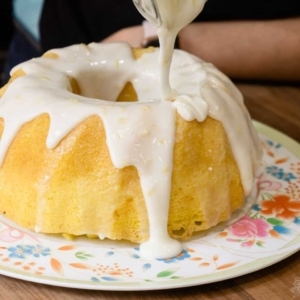 pouring lemon glaze over a lemon bundt cake