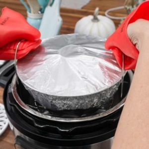 removing a cooked bundt cake from the instant pot using mini mitts