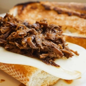 making a french dip sandwich on french scratch bread with provolone cheese