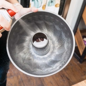 spraying a bundt cake pan with cooking spray