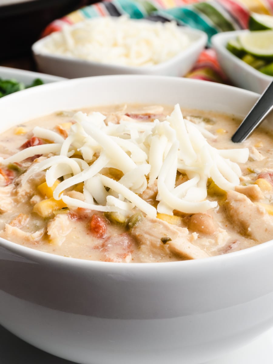 a bowl of white turkey chili with white shredded cheese on top