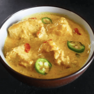 indian fish curry served in a bowl garnished with jalapeno slices