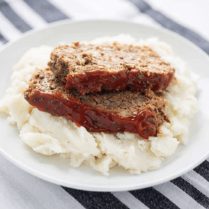 a plate with meatloaf served on top of mashed potatoes