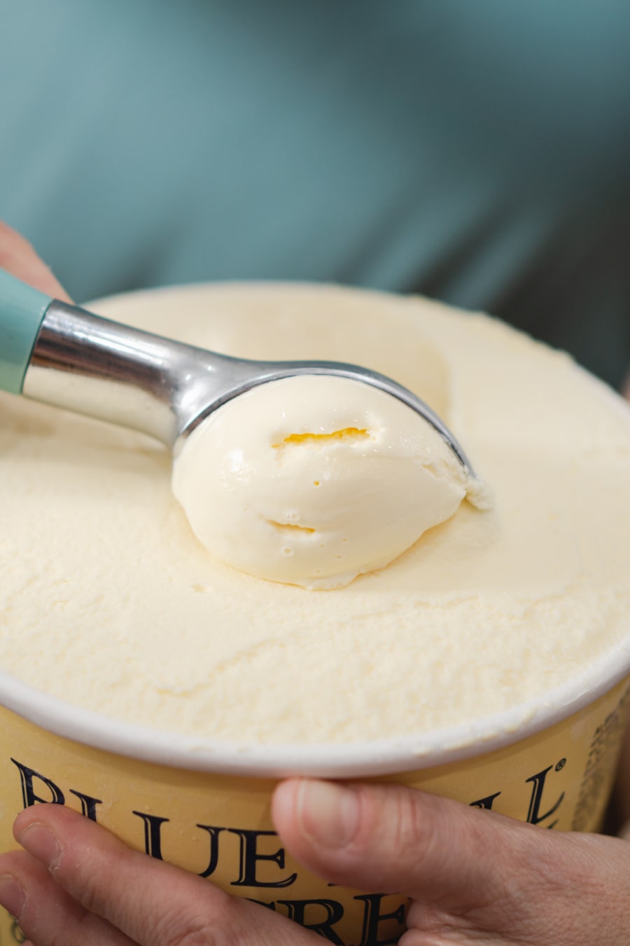 scooping out ice cream from a tub of vanilla ice cream