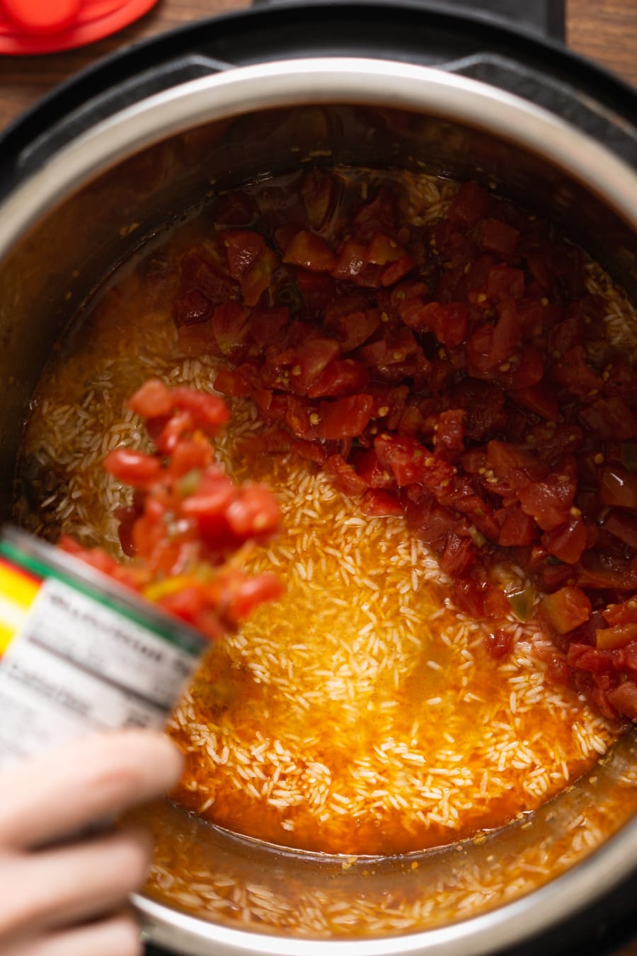 adding a can of rotel to the instant pot layering it over ground beef and rice