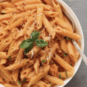 overhead shot of a bowl of pasta with tomato cream sauce garnished with basil